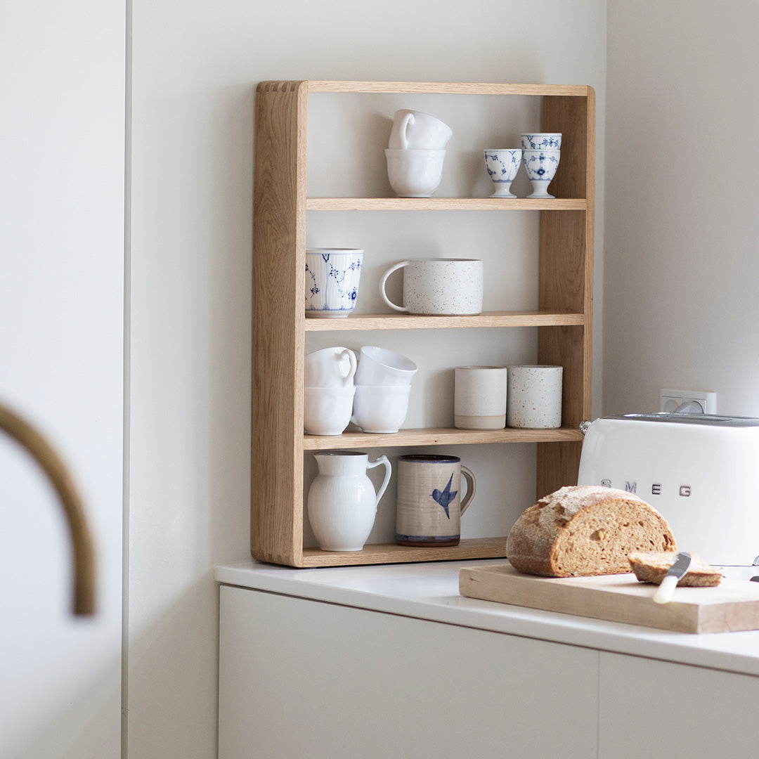 "Wooden shelf displaying white and blue patterned mugs, cream and speckled ceramic cups."