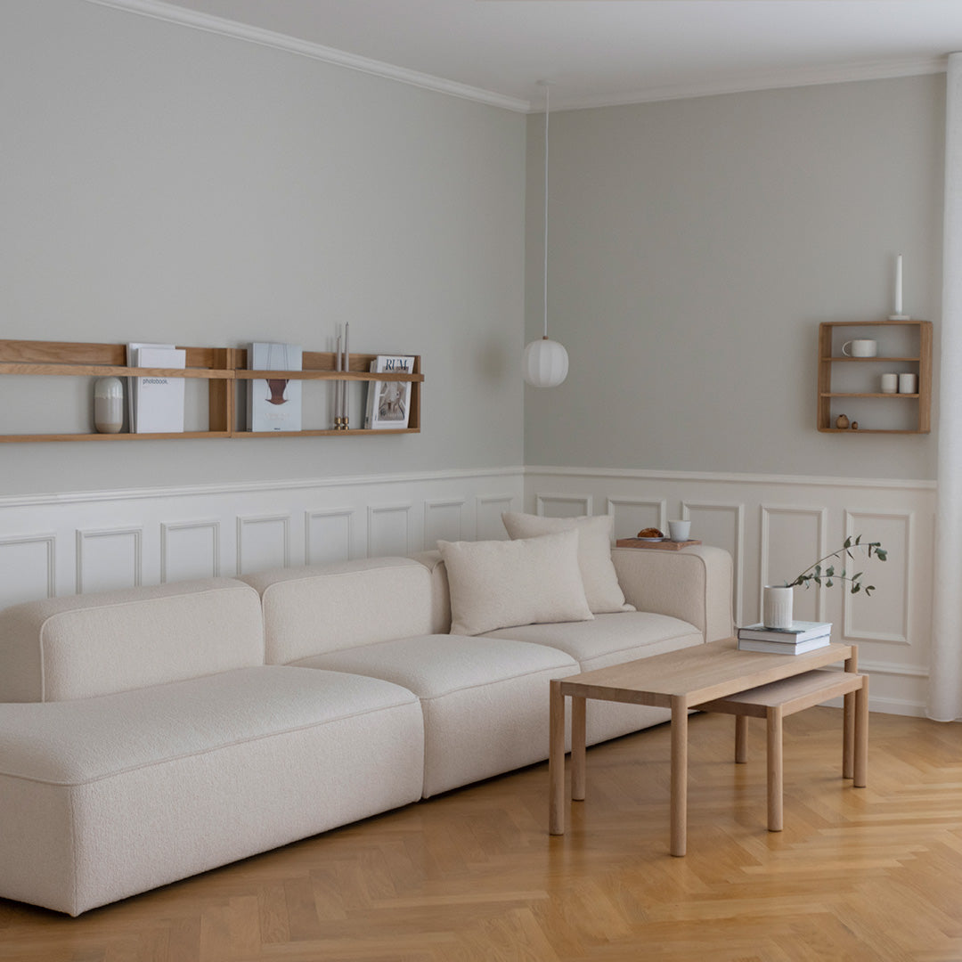 Beige sofa with light wood table in a soft gray room, featuring neutral decor and subtle textures for a cozy ambiance.
