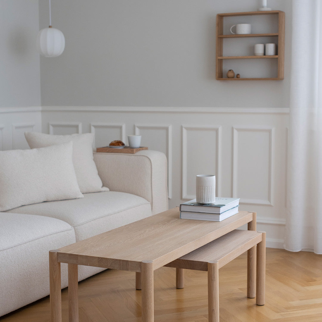 Light beige sofa with textured cushions, natural wood coffee table, pastel gray walls, and soft white decor accents.