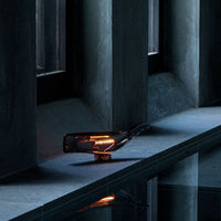 Elegant amber glass lamp with sleek black and gray accents, reflecting softly on a stone surface.