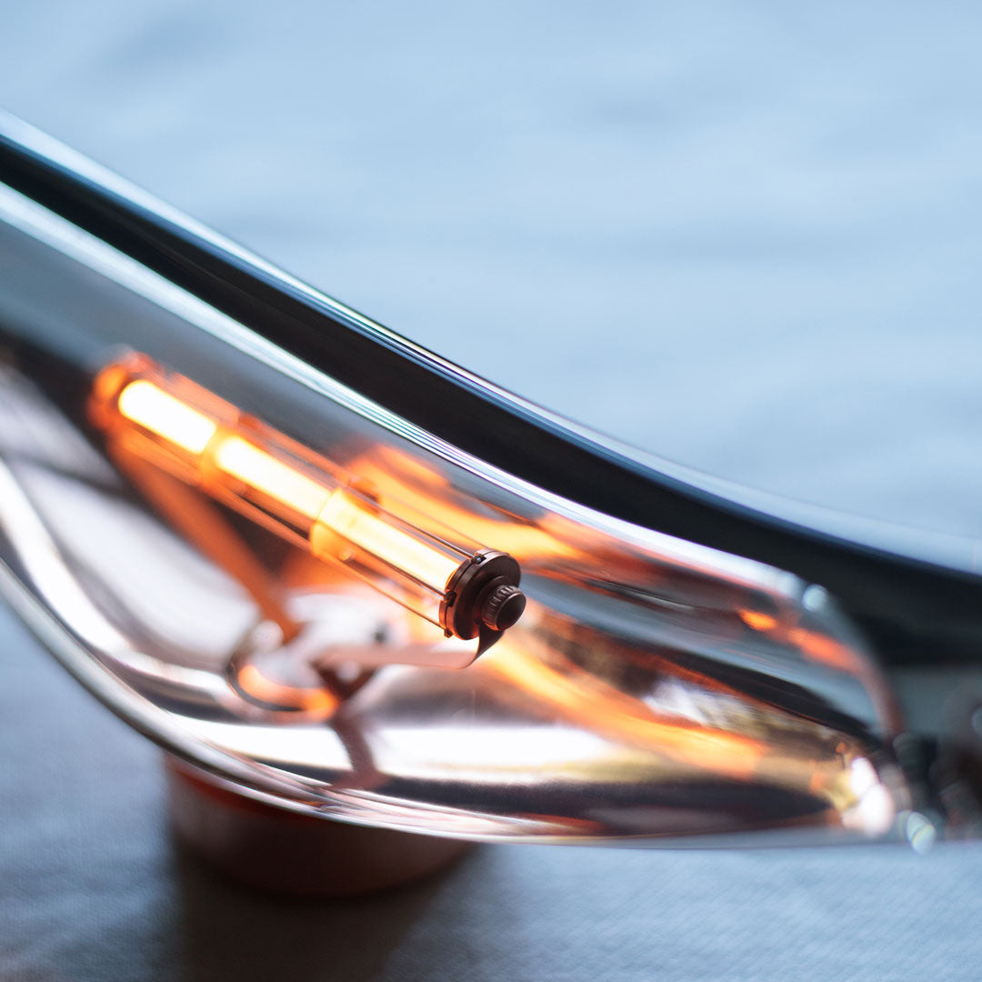 Close-up of reflective chrome with vibrant orange accents against a soft blue background. Modern and sleek design details.