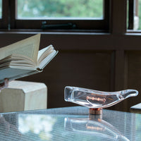 Clear glass vase with a sleek design and copper accent, set against a warm wooden background.