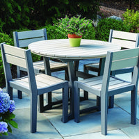 Round patio table set in soft gray with light gray slats, surrounded by greenery and blooming flowers.