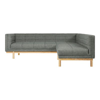 Modern grey upholstered sectional sofa with a quilted pattern and light wooden legs. Perfect for contemporary living spaces.