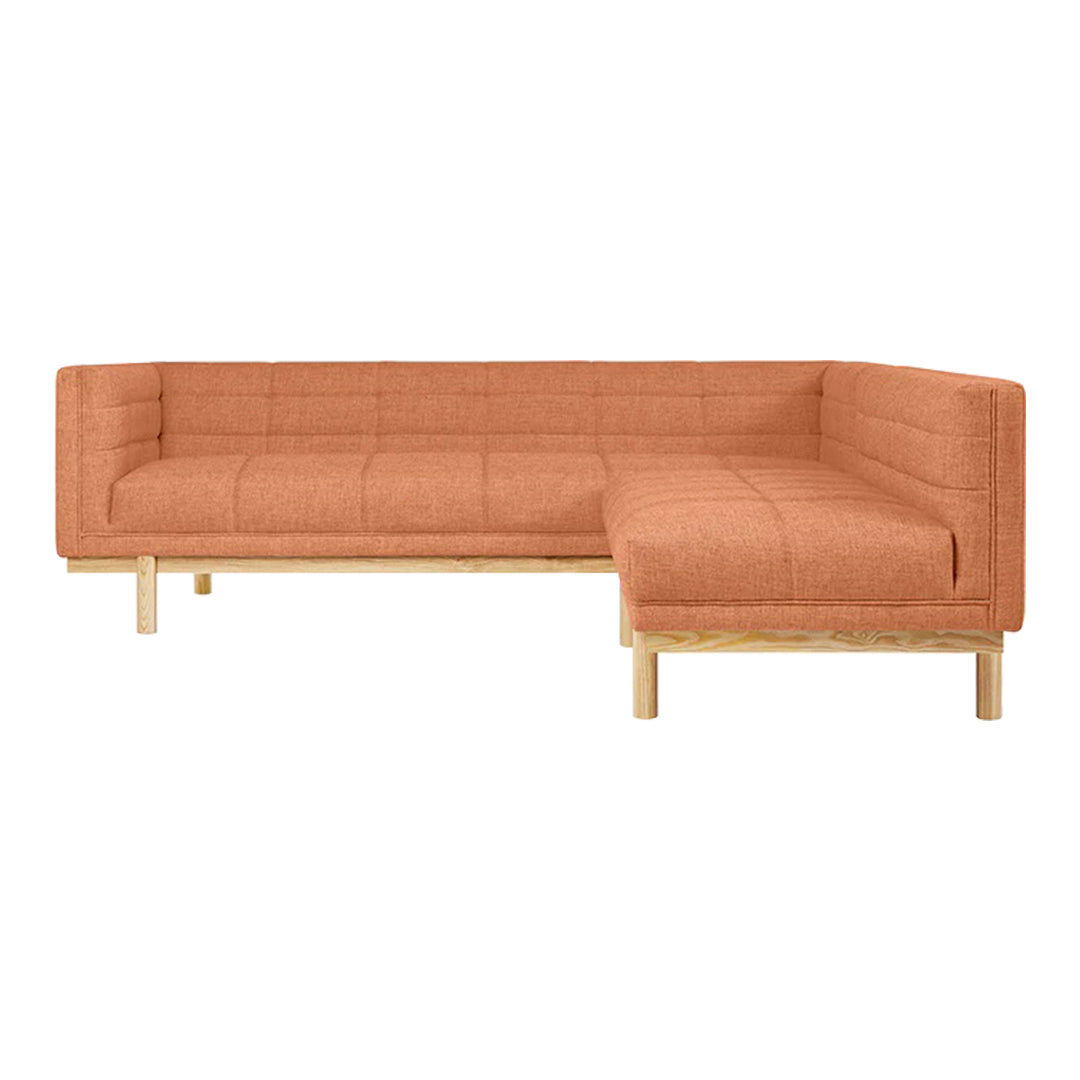 Rust-colored sectional sofa with a quilted pattern, complemented by natural wood legs. Modern and stylish design.