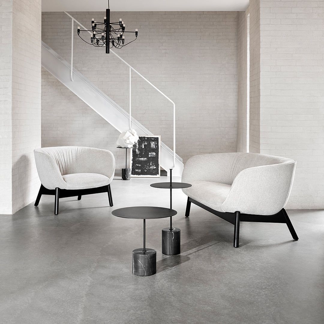 Gray and white upholstered chairs with black legs, complemented by sleek black circular tables in a modern living space.