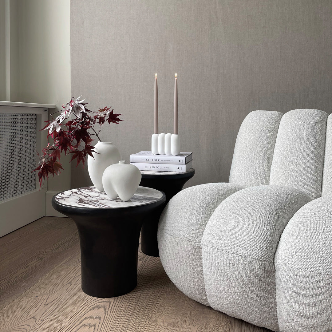Textured white sofa with black accent tables, featuring soft gray tones and minimalistic decor elements.