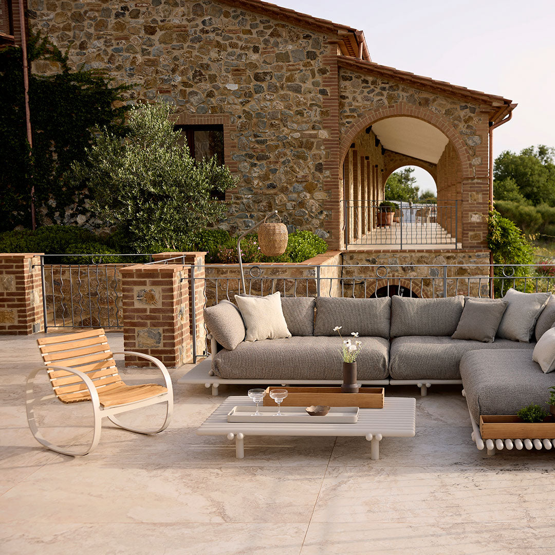 "Gray outdoor sectional sofa with soft cushions, paired with a minimalist white coffee table and natural wood accents."