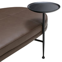 Round black side table with sleek metal legs, paired with a rich brown padded surface. Minimalist design and elegant colors.
