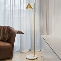 Gold metal floor lamp with a conical shade, featuring a sleek white marble base. Elegant and modern design.