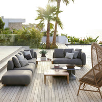 Stylish gray outdoor sofa set with soft cushions, complemented by natural wooden accents and palm tree backdrop.
