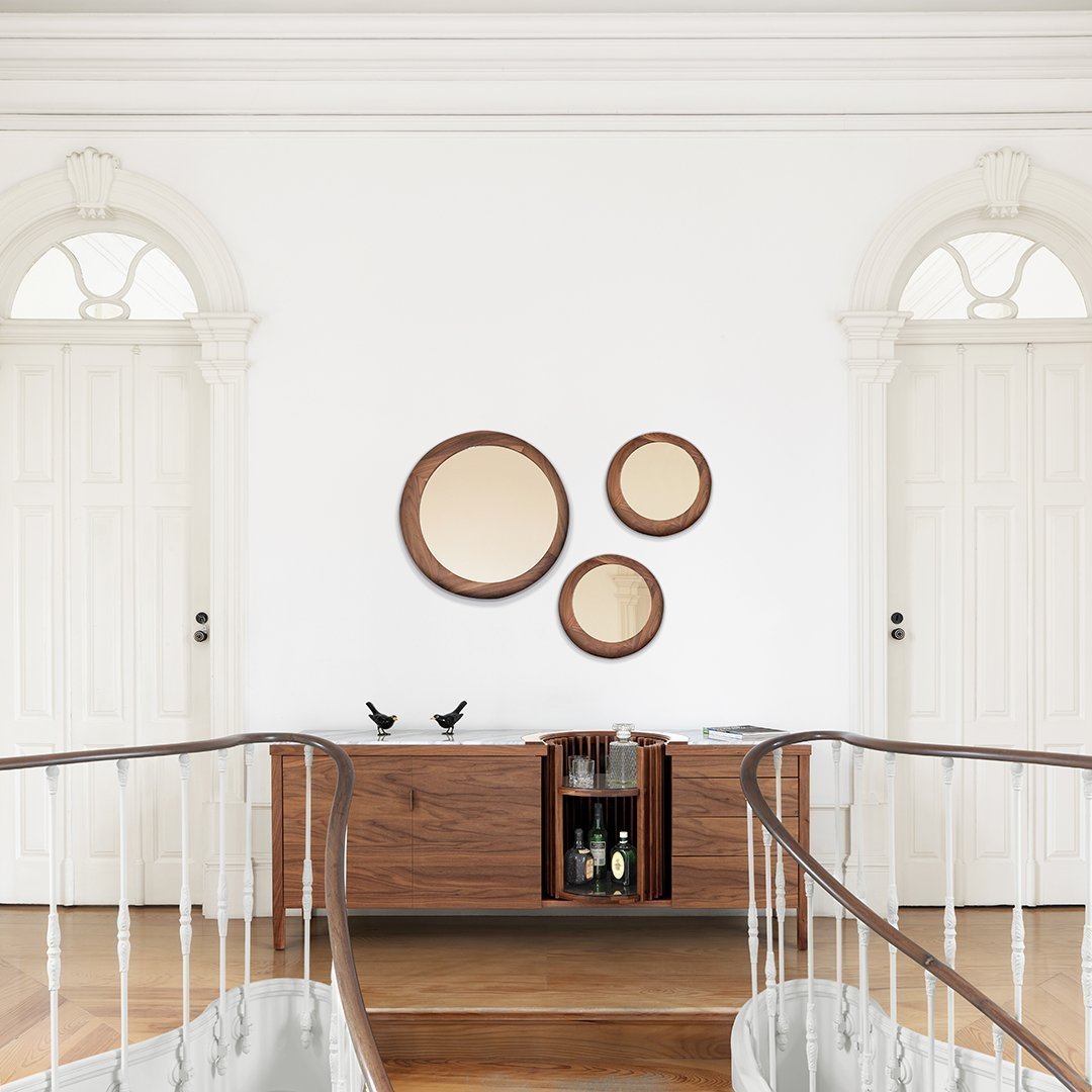 Set of three round mirrors with wooden frames, featuring soft beige surfaces against a crisp white wall.