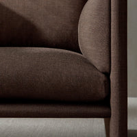 Brown textured fabric couch with smooth contours and a minimalist design against a soft, neutral background.