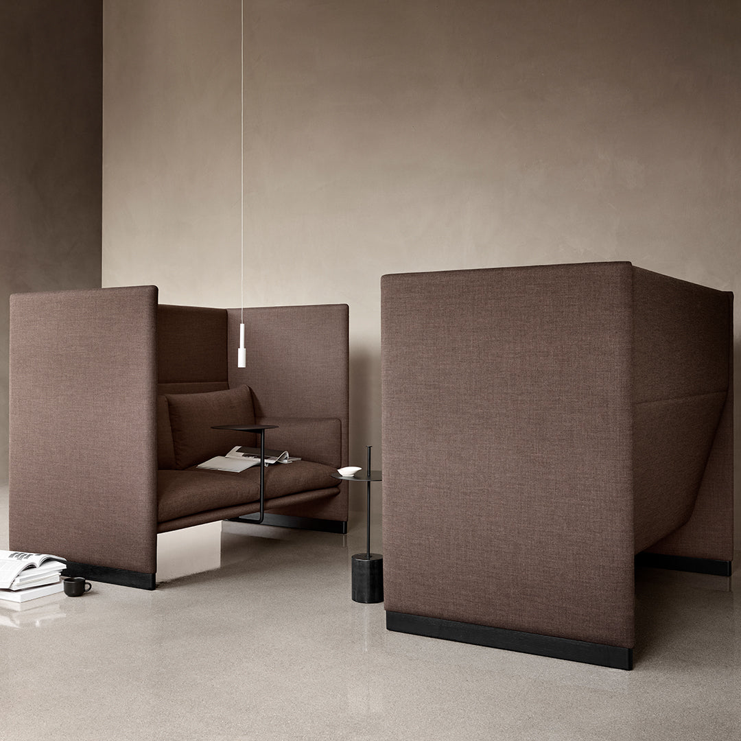 Two modern brown upholstered seating pods with sleek lines set against a neutral backdrop.