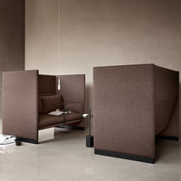 Two modern brown upholstered seating pods with sleek lines set against a neutral backdrop.
