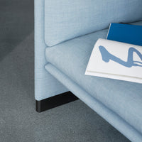 Light blue fabric upholstery with a smooth texture, paired with a dark black base.