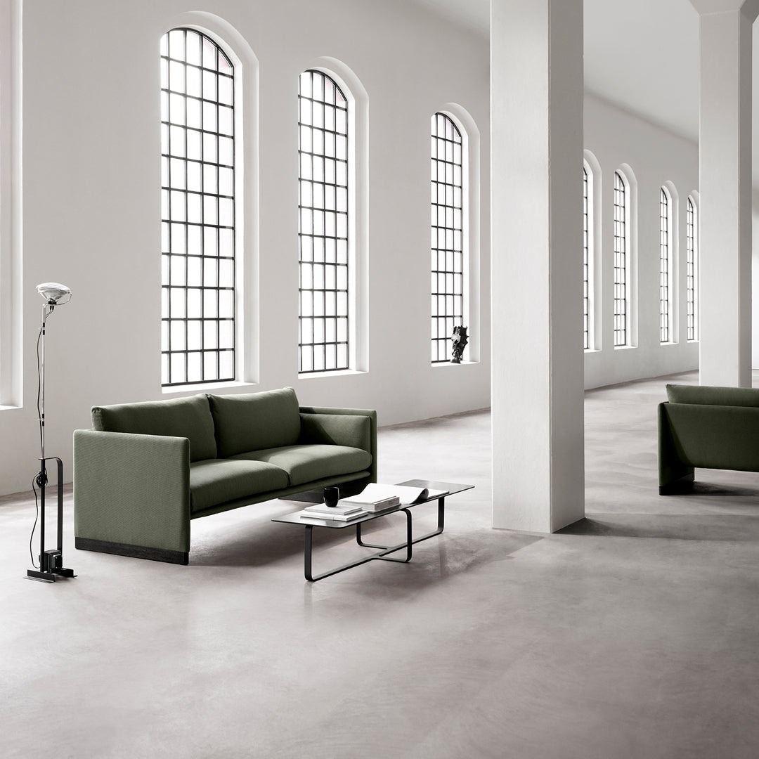 Modern green sofa set with sleek lines in a minimalist space, featuring neutral walls and large windows.