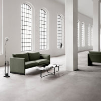 Modern green sofa set with sleek lines in a minimalist space, featuring neutral walls and large windows.