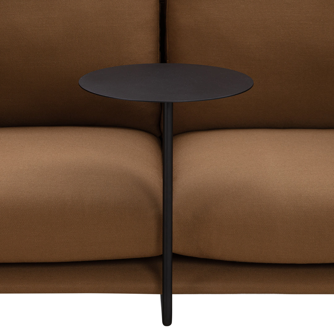 Elegant black side table between brown couch cushions, featuring a sleek, minimalist design and smooth surface.