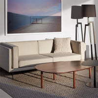 Beige sofa with textured cream pillow, brown wooden coffee table, neutral tones and soft shadows in a modern setting.