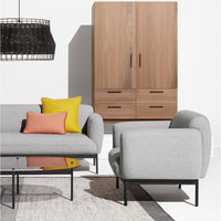 Gray sofa with colorful throw pillows in yellow and orange, paired with a wood cabinet and modern glass coffee table.
