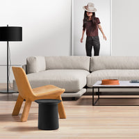 Modern living room featuring a beige sofa, yellow accent chair, and black side table on light wood flooring.