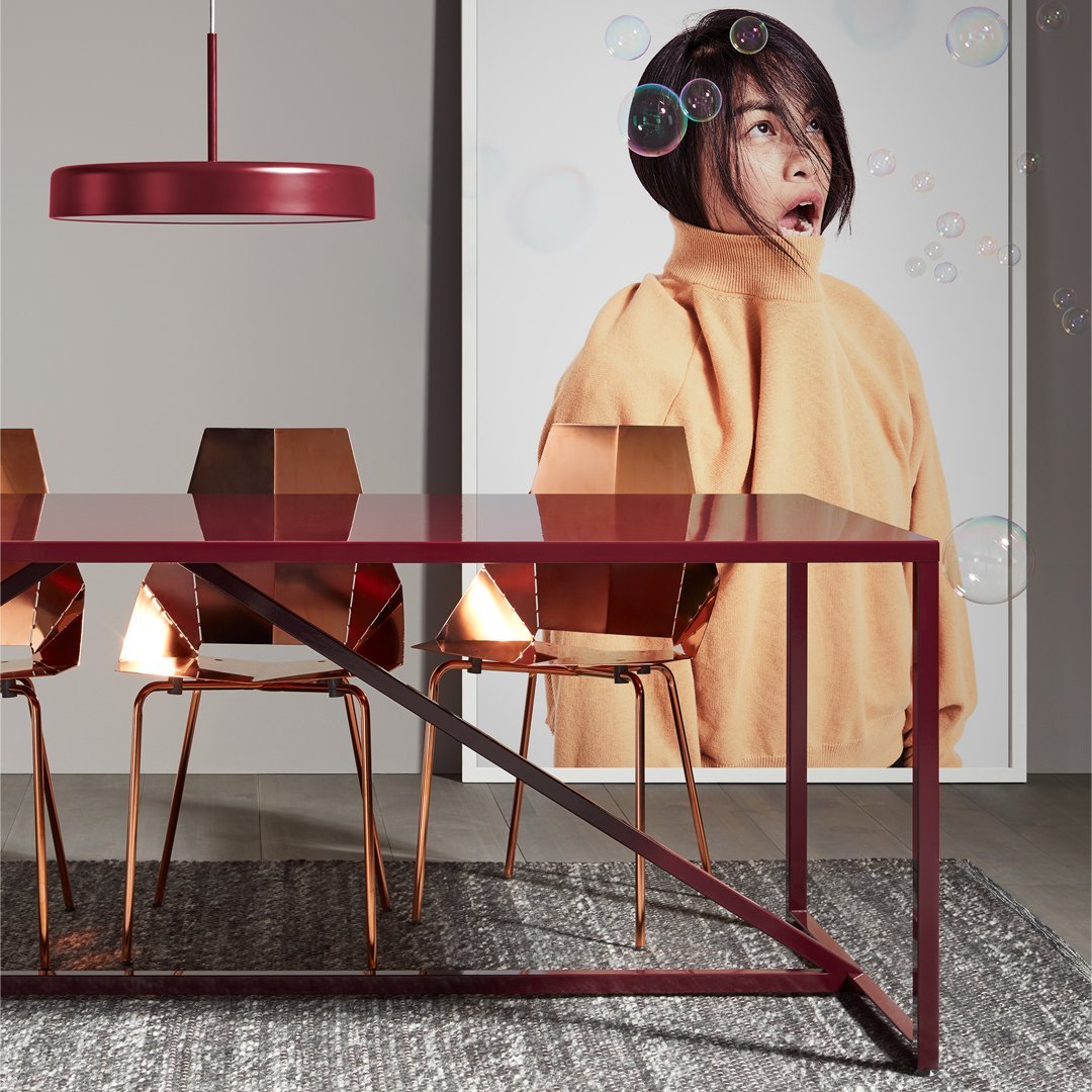 Contemporary dining room featuring a burgundy table, golden chairs, and a textured gray rug.