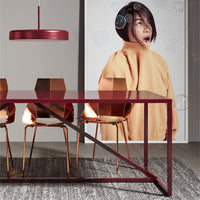 Contemporary dining room featuring a burgundy table, golden chairs, and a textured gray rug.