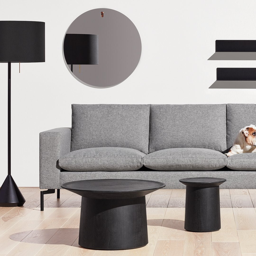 Stylish gray sofa with black round tables and lamp, featuring sleek modern lines and minimalistic patterns.