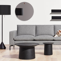 Stylish gray sofa with black round tables and lamp, featuring sleek modern lines and minimalistic patterns.
