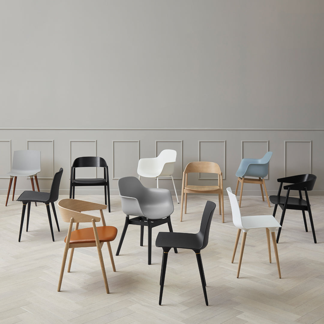 Colorful modern chairs in various hues: black, white, grey, pastel blue, and natural wood, featuring diverse patterns and styles.