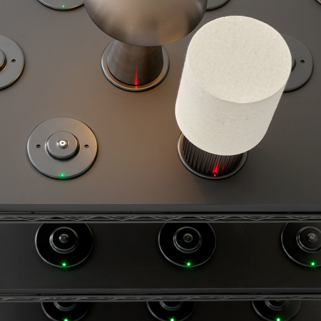 Modern lamp in white and black on a sleek black surface with green and red LED accents. Minimalist design.