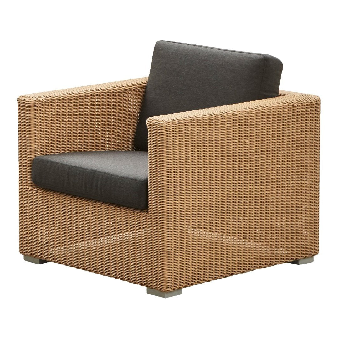 Natural woven rattan chair in light brown with a contrasting dark gray cushion. Modern, textured design for indoor/outdoor use.