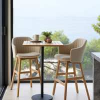 Neutral beige chairs with textured fabric on wooden legs, paired with a wooden table against a coastal backdrop.