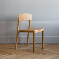 Light oak chair with a smooth finish, minimalist design, and subtle natural grain patterns against a gray backdrop.