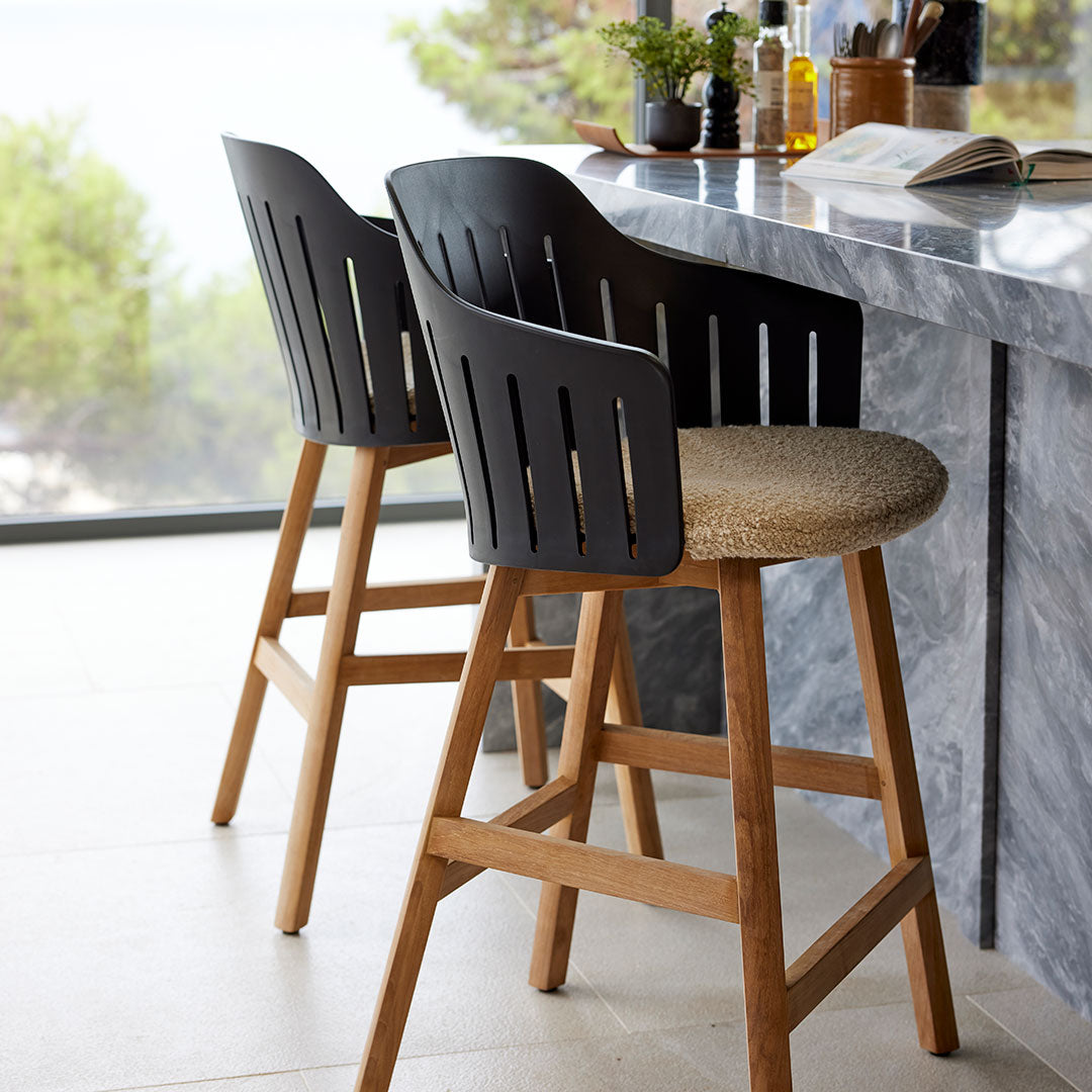 Two stylish bar stools featuring black slatted backs and natural wood legs with a woven seat. Modern and minimalist design.