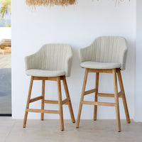 "Two cream-colored bar stools with ribbed upholstery and wooden legs against a minimalist backdrop."