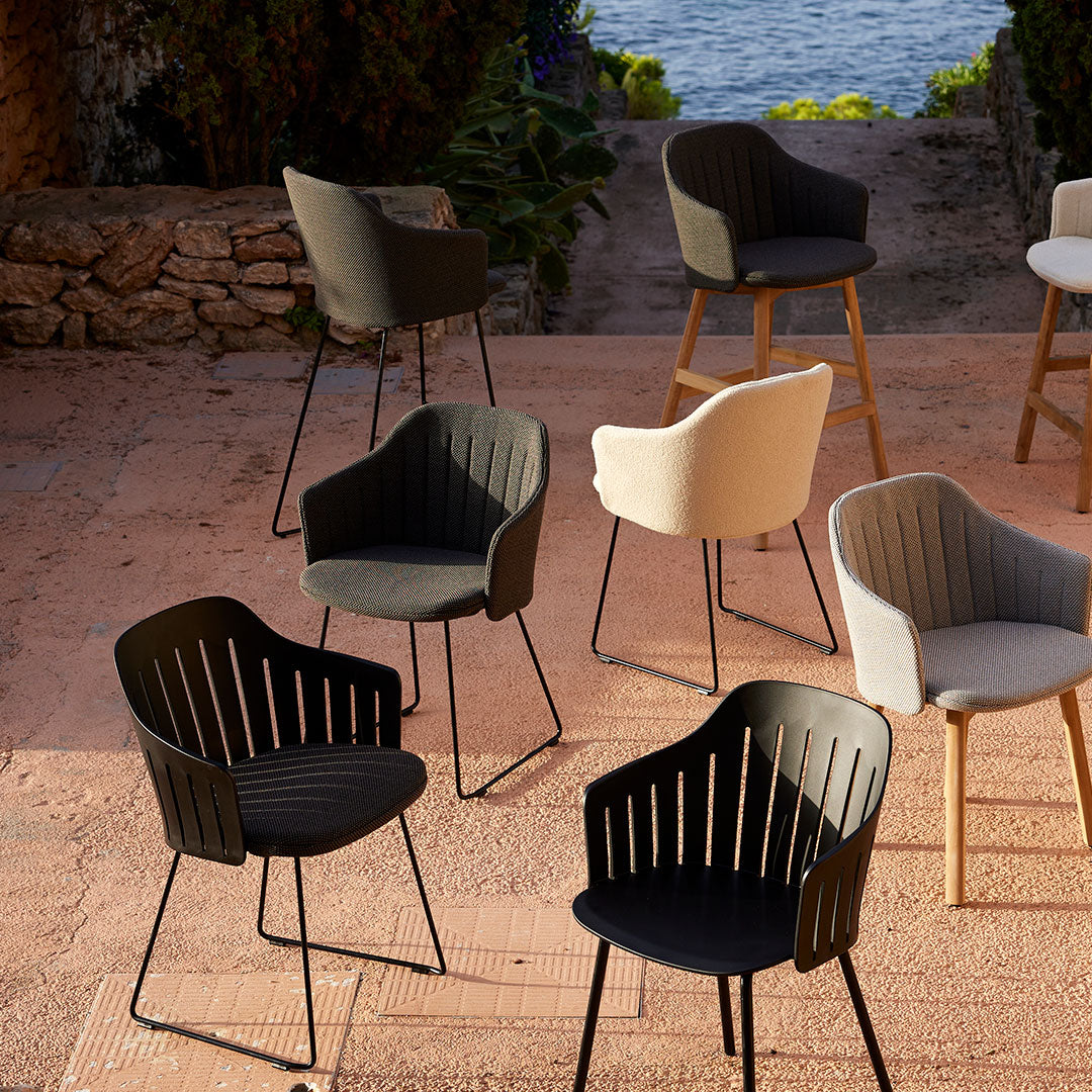 Set of modern chairs in black, white, and beige with ribbed patterns, on a textured outdoor surface.