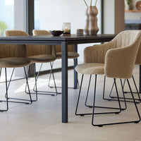 Beige textured chairs with sleek black metal legs, set against a minimalist table in a light, airy dining space.