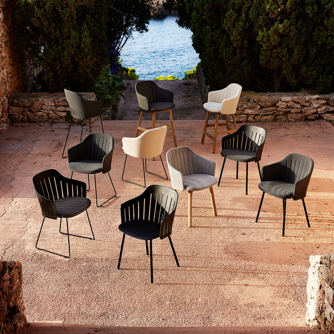 Set of modern chairs in black, white, and gray, featuring textured patterns and sleek lines, on a scenic outdoor patio.