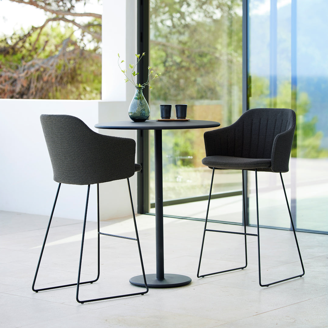 Stylish black bar stools with ribbed fabric pattern paired with a sleek black round table in a modern setting.