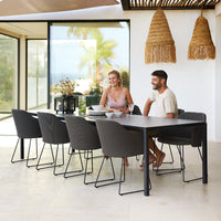 "Modern outdoor dining set with sleek gray chairs, a dark table, and natural woven decor, perfect for stylish gatherings."