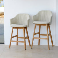 Cream ribbed upholstered bar stools with natural wood legs, set against a bright, minimalist background.