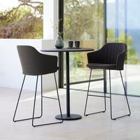 Modern black and gray bar stools with a sleek metal frame and ribbed upholstery, paired with a minimalist black table.