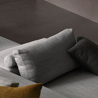 Two textured throw pillows in shades of gray, dark green, and mustard yellow on a flat surface.