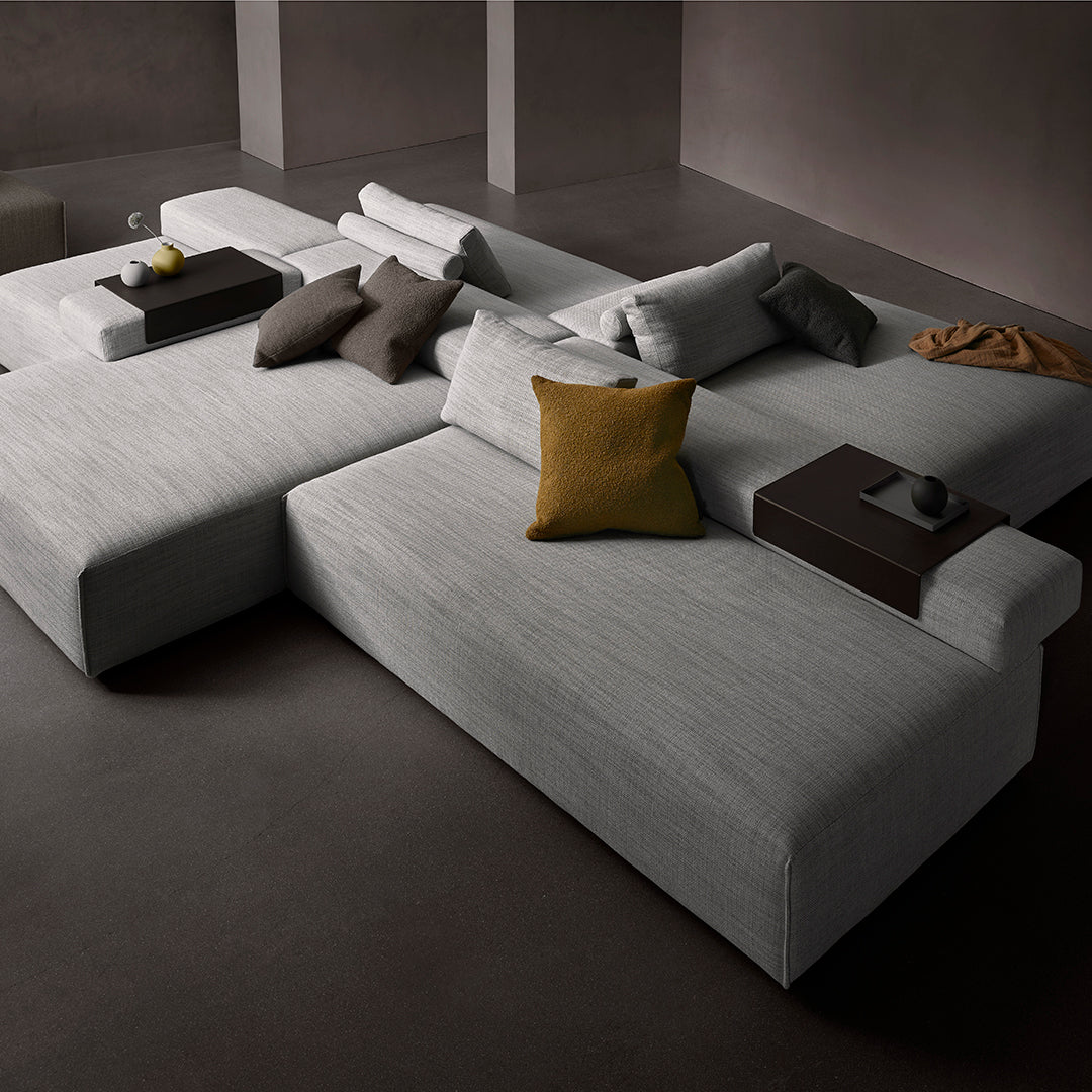 Stylish modular sofa in light gray fabric, featuring textured cushions in varied shades of gray and mustard yellow accents.