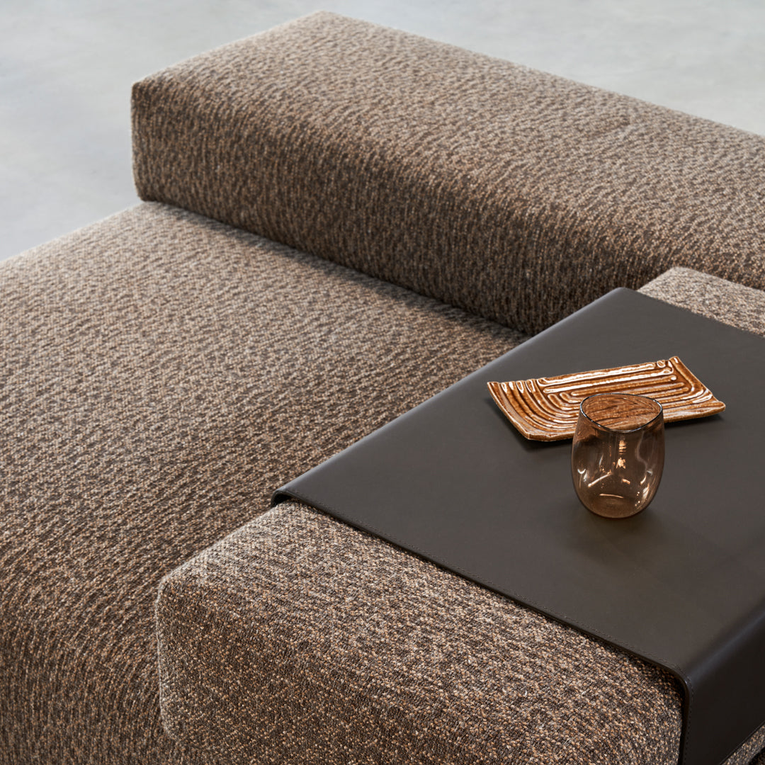Textured brown and tan patterned upholstery on a modern couch with a sleek black side table.