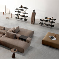 Modern living room with a neutral beige sofa and brown accent pieces, set against a minimalist gray backdrop.