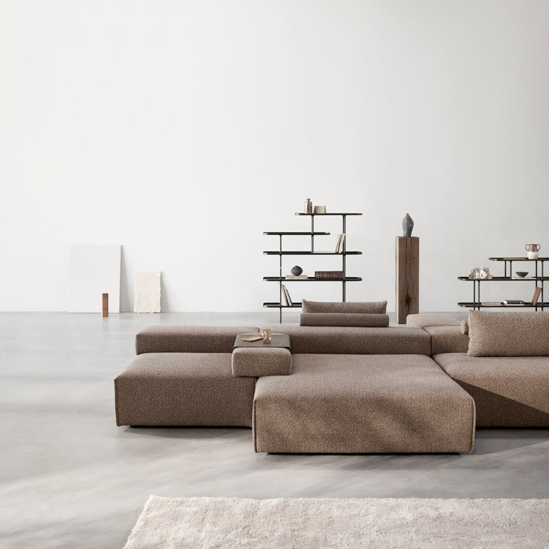 Modern sectional sofa in warm beige with a smooth, textured fabric, complemented by minimalist decor in a neutral space.
