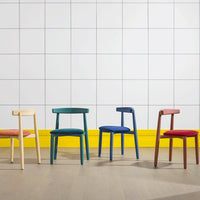 "Colorful chairs in yellow, blue, green, red, and natural wood against a white tiled background."